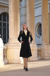 a lady in a white shirt, a black coat and a pair of brown pants